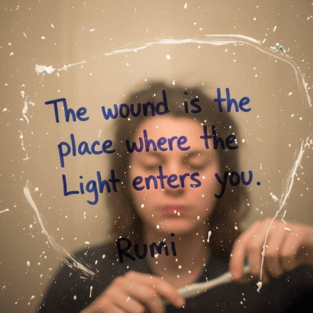 Blurry reflection of a person brushing teeth in a mirror with a Rumi quote written in blue marker and toothpaste splatter.