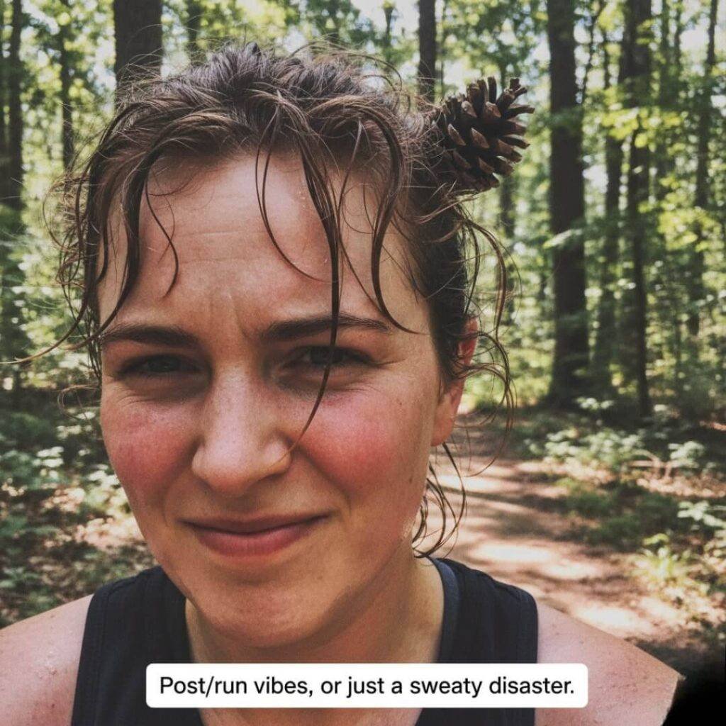A sweaty, off-center selfie of a person on a trail, with a half-smirk and half-grimace, and a pinecone stuck in their hair.