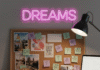 Achieve Your Dreams: Learn How to Get Unstuck and Succeed A slightly blurred photorealistic image of a cluttered desk with a half-finished vision board, a glowing neon sign with the word "Dreams" flickering slightly, and a cracked coffee mug with a motivational quote. Scattered sticky notes with doodled stars and question marks are visible. The color palette is muted pastels contrasted with pops of neon pink.