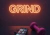 The Ultimate Gym Motivation Playlist to Power Your Workout A blurry, photorealistic image of a gym bench with tangled, sweaty earbuds, a cracked phone screen playing music, a neon "GRIND" sign in the background, and a pink dumbbell in the corner.