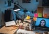 Self-Motivation Secrets: Essential Tips Every College Student Needs to Thrive A person's messy dorm desk at 2 a.m., with a laptop displaying a video call, books, a pizza box, and sticky notes saying "You got this!" and "Essay due tomorrow!" A rubber duck sits atop a stack of books.